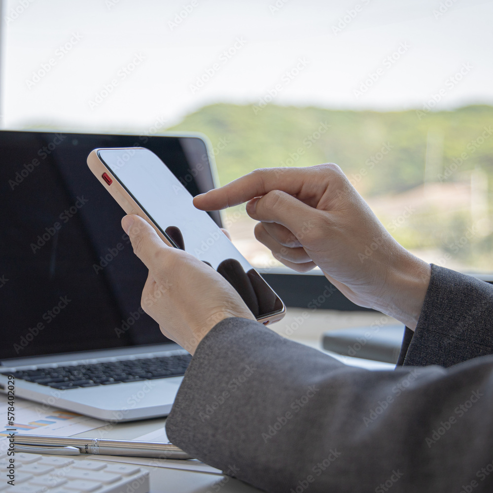 Finance workers are reviewing the company's financial data on a laptop and using smartphones to communicate or chat with the team at social distances, Working during the virus outbreak.