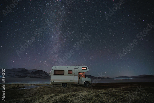 motor home under the starry sky against the backdrop of the mountains in winter