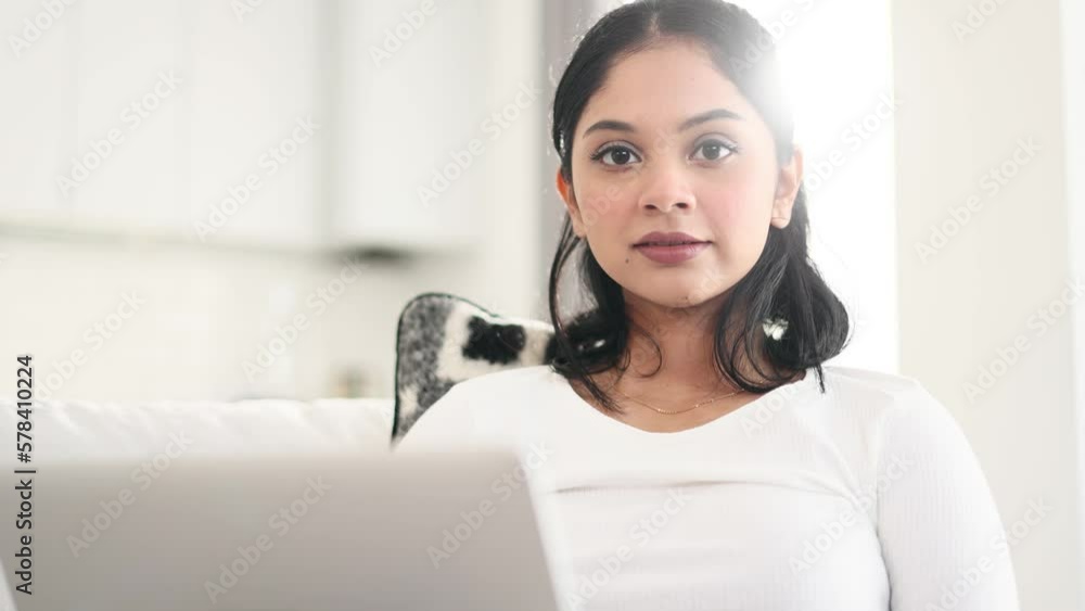 Portrait of young indian woman relax at home or working online typing browsing products in internet store reading news checking email or social media profile on laptop computer and looking at camera Portrait of young indian woman relax at home or working online typing browsing products in internet store reading news checking email or social media profile on laptop computer and looking at camera