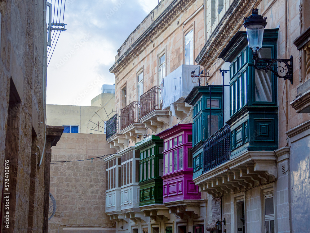 Fragment of the building's facade with traditional wooden ornate balconies painted in Valletta, Malta. High quality photo
