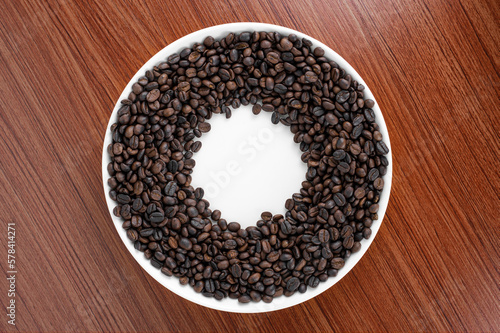 Coffee beans are placed on a plate with a wooden board in the background. There is space for text or something.