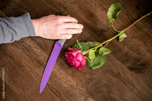 Hand holding knife on floor next rose murder scene
