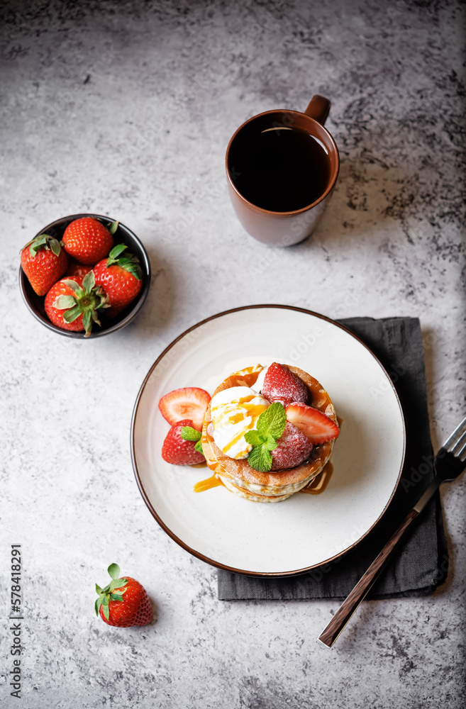 Sweet souffle pancakes decorated with fresh strawberries in a plate