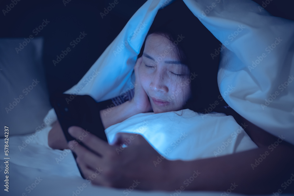 Asian woman playing game on smartphone in the bed at night,Thailand people,Addict social media Asian woman playing game on smartphone in the bed at night,Thailand people,Addict social media