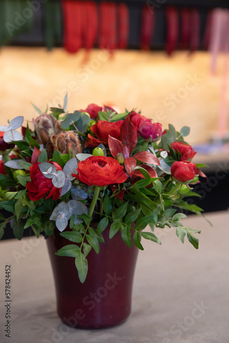 Beautiful flower arrangement of red persian buttercups, eucalyptus branches in vase at garden flower shop.