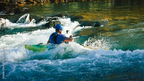 Caucasian man kayaking upstream on the whitewater rapids, paddling hard on the turbulent river photo