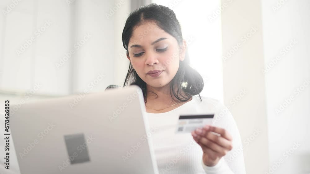 Portrait of young indian woman paying with credit card on laptop computer at home Happy customer doing payments online shopping in internet store and receiving cashback Easy pay concept Portrait of young indian woman paying with credit card on laptop computer at home Happy customer doing payments online shopping in internet store and receiving cashback Easy pay concept
