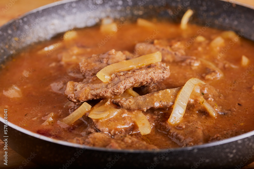 English classic liver and onions in gravy resting in a pan. English classic liver and onions in gravy resting in a pan.