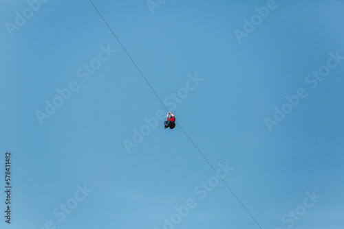 Man having fun on a zip line at summer against blue sky