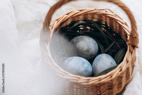 Tableau sur toile Easter eggs pastel colored in a small wicker basket on light background