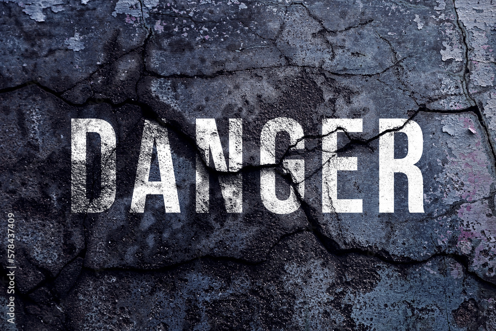 Danger text written with broken cement wall, Danger word on street. Danger text written with broken cement wall, Danger word on street.