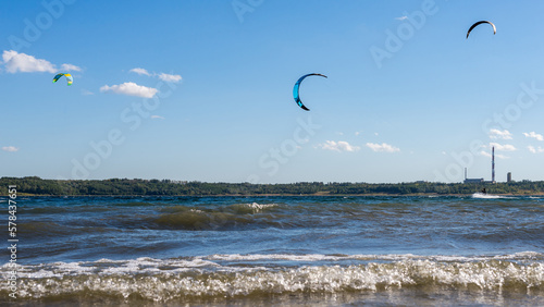 Kitesurfers flying over the lake. Kiteboarding (kitesurfing) on a beautiful sunny and windy day