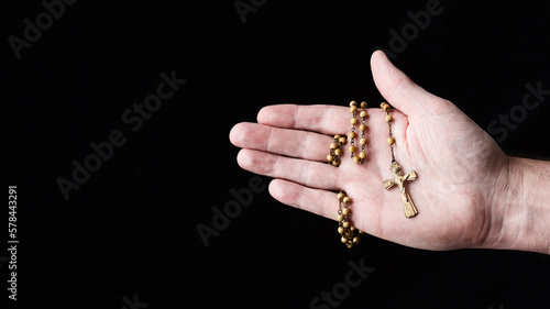 Male hand holding a crucifix pendant on dark background © Kevin Brine