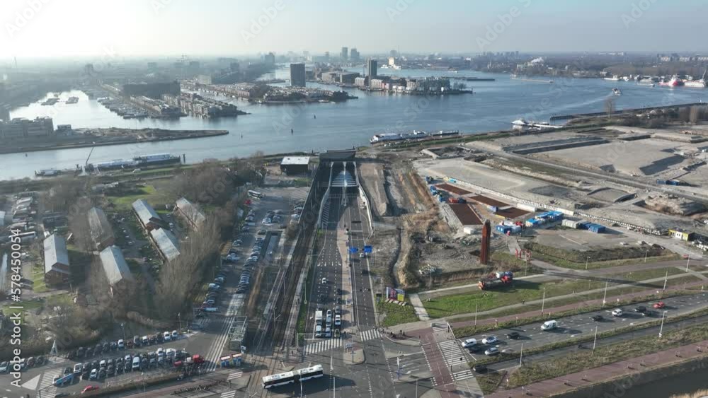 An aerial perspective of Amsterdam's modern transport infrastructure, with the Piet Hein Tunnel and canal effortlessly connecting the city center to Zeeburgereiland. An aerial perspective of Amsterdam's modern transport infrastructure, with the Piet Hein Tunnel and canal effortlessly connecting the city center to Zeeburgereiland.