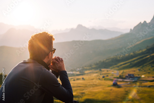 Fototapeta Person mit Sonnenbrille sitzt in den Bergen bei Sonnenuntergang und genießt die