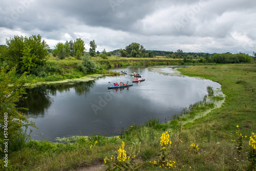 A landscape with floating kayaks along a pure river untouched by civilization with herbs along the banks.