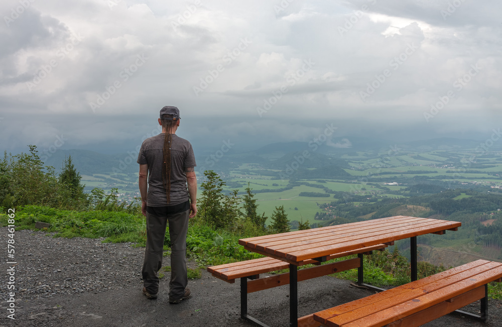 Wooden table and benches, hiker with dreadlocks  and view from Velky Javornik to Frenstat nad Radhostem, Beskid Mountains
