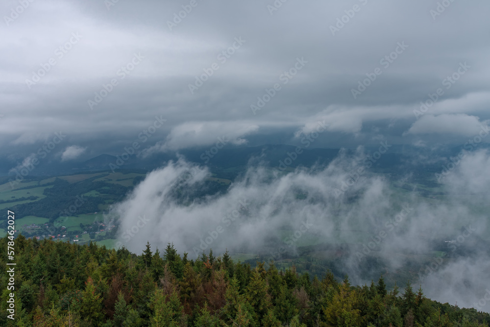 View from lookout tower Velky Javornik to Beskid Mountains in summer cloudy evening. The fog rises from the valley to the top