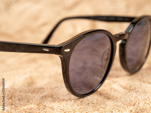 Stylish sunglasses. Sunglasses in a dark frame on a sandy background. Close-up.