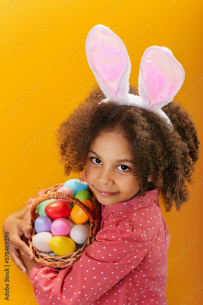 A Black girl with rabbit ears on her head with a basket full of colored eggs. A Black girl with rabbit ears on her head with a basket full of colored eggs.