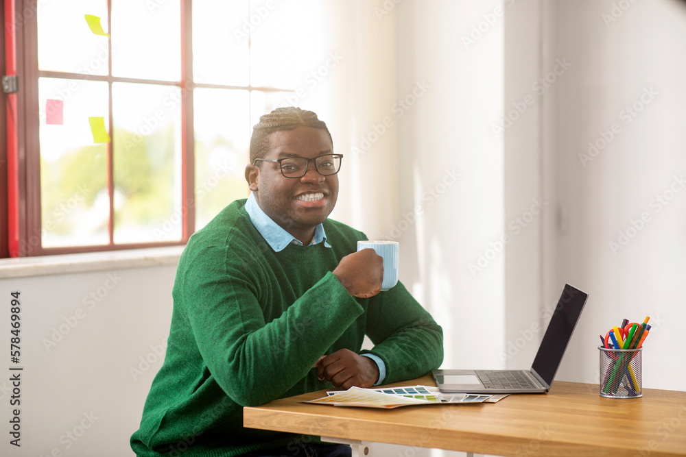 Successful Black Male Designer Using Laptop Enjoying Coffee At Workplace Successful Black Male Designer Using Laptop Enjoying Coffee At Workplace