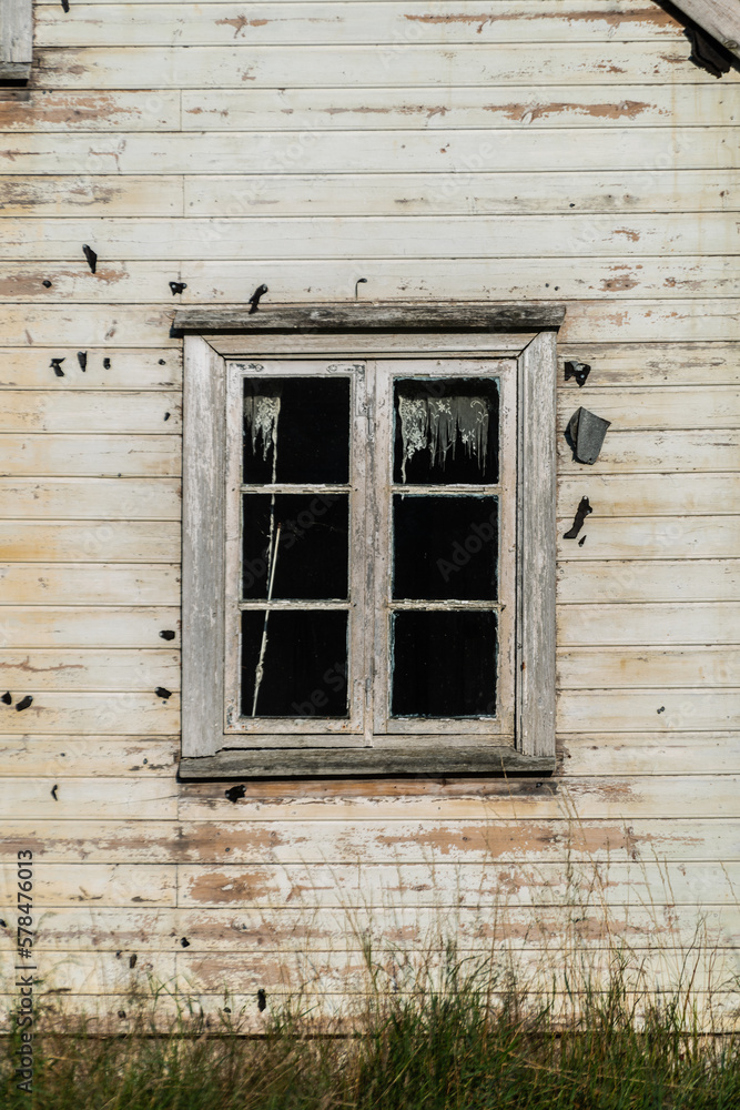 Window of old abandoned white wooden house.