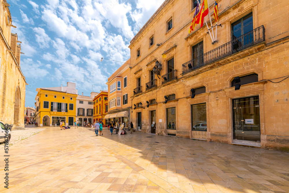A colorful street of shops and cafes at the Ciutdadella Cathedral Plaza square in the medieval old town district of Ciutadella de Menorca, Spain.