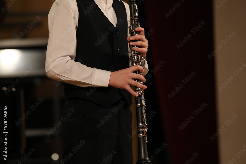 Fototapeta premium A young clarinetist musician stands with a musical instrument in his hands
