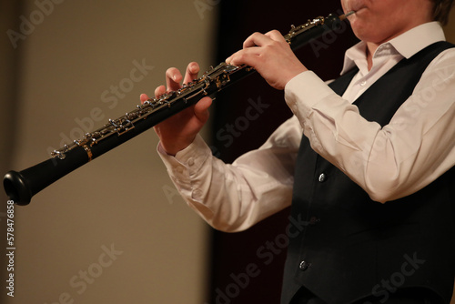 Person playing the black clarinet details of a musical instrument in the hands of a young musician close up