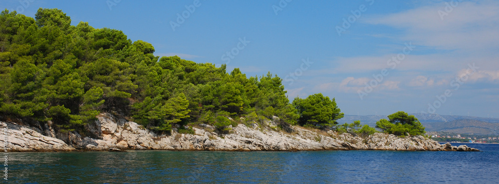 Rocky limestone coast of the Adriatic Sea covered with pine forest. Croatia coastline.