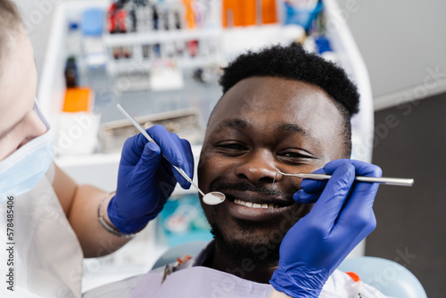 Happy african american patient of dentistry. Teeth treatment. Handsome african man sitting in dental office and smiling. Dentist visiting and consultation.
