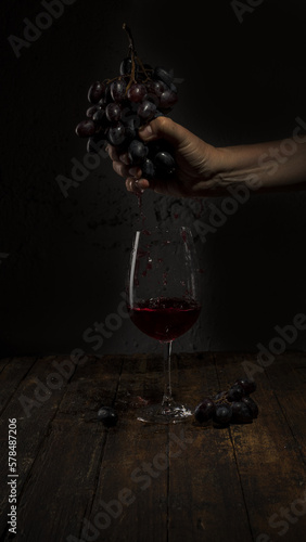 
Vino tinto en una copa y uvas maduras sobre fondo negro. photo