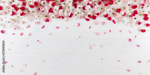 Pink, white and red flowers and petals on a white wooden table, image created with AI technology.