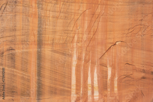 A red sandstone cliff in Zion Nat. Park, Utah, USA shows horizontal and diagonal striation layers and vertical streaks from water dripping down the cliff causing oxidization to color the stone face. photo