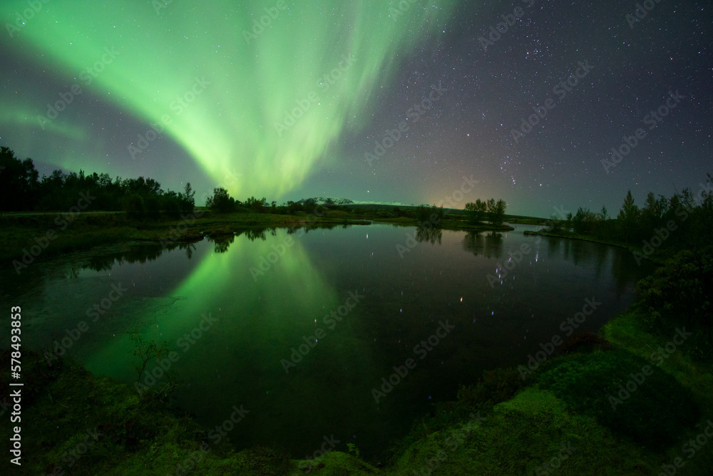 Bright aurora borealis mirror reflection in lake, Thingvellir Iceland