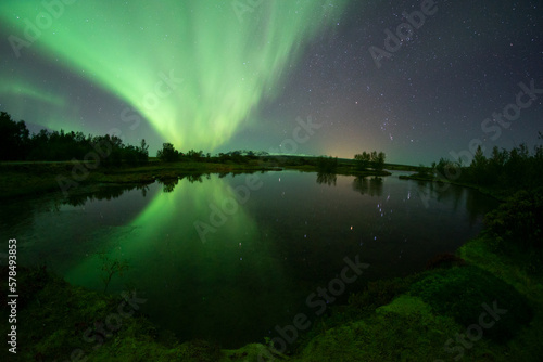 Bright aurora borealis mirror reflection in lake  Thingvellir Iceland