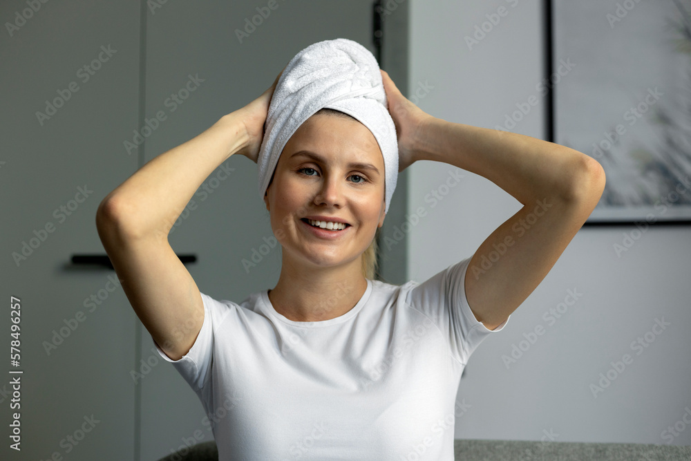 Beautiful smiling woman with head wrapped in towel looking at camera after shower, morning routine. Beauty and skin care concept Beautiful smiling woman with head wrapped in towel looking at camera after shower, morning routine. Beauty and skin care concept