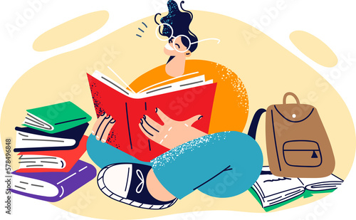 Young happy girl student sits on floor reading books and preparing for difficult exam