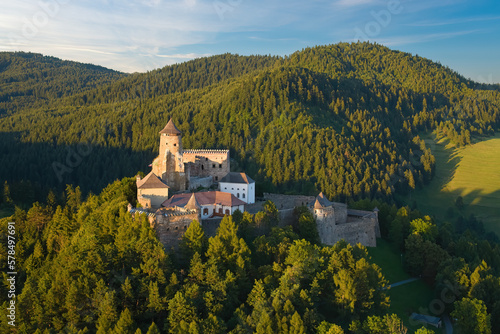 Lubovna Castle, Spis area, Slovakia. Medieval border castle, situated on a rock above wooded hills against blue sky, white clouds, summer. Travelling through the sights and castles of Slovakia.