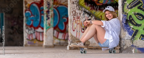 Woman posing with a skateboard in an abandoned building