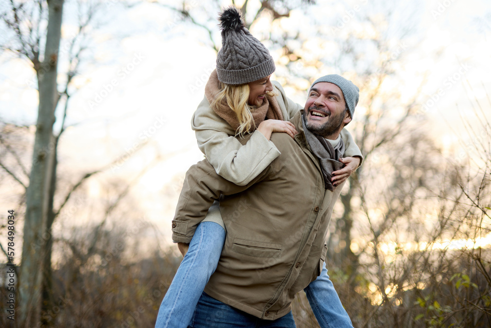A handsome man giving his girlfriend a piggyback ride outdoors A handsome man giving his girlfriend a piggyback ride outdoors