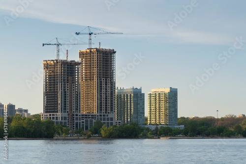 Canvas Print Two tall construction cranes at the site by the lake
