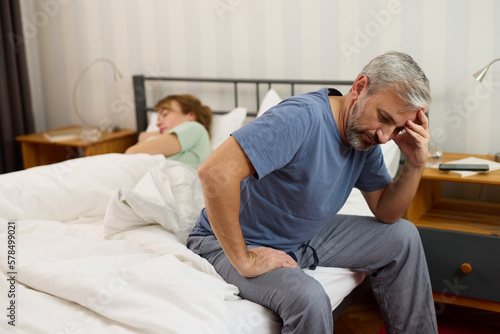 Mature man looking worried while his wife sleeps in the background © Stockphotodirectors