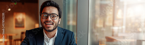 Smiling businessman working with graphs and charts at modern cafe. Blurred background
