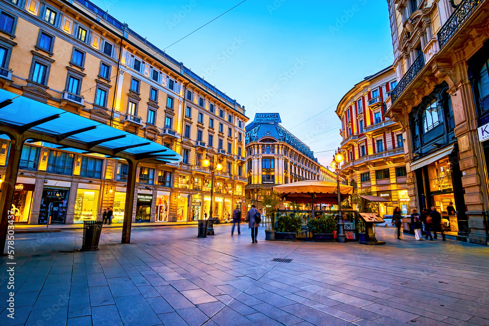 Via Dante street with bright illuminated shop windows in evening, on April 11 in Milan, Italy