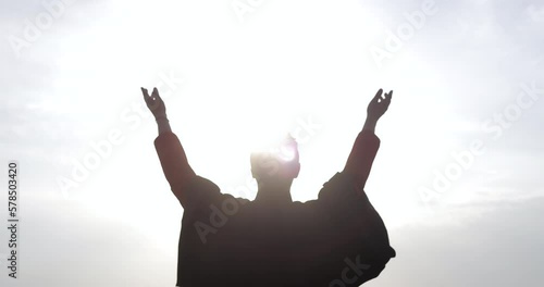 The orthodox priest raises his hands to the rising sun and prays at the sea.