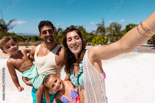 Happy biracial family taking selfie at beach