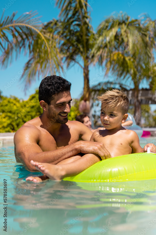 Happy biracial father and son playing together in swimming pool Happy biracial father and son playing together in swimming pool