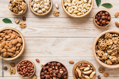 mixed nuts in wooden bowl. Mix of various nuts on colored background. pistachios, cashews, walnuts, hazelnuts, peanuts and brazil nuts