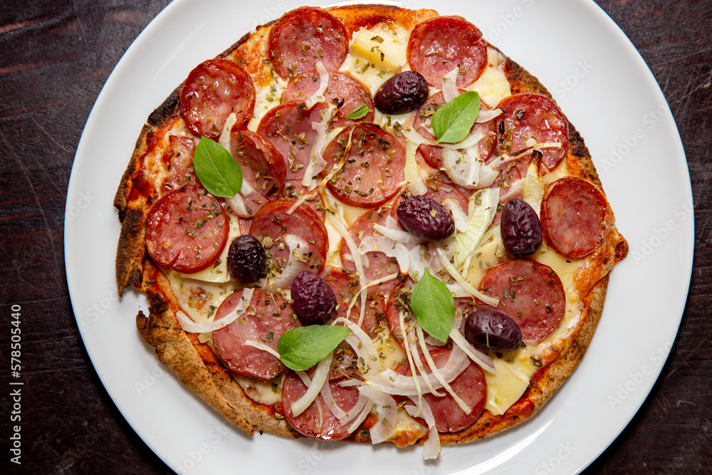 Traditional rustic pizza with pepperoni, black olives, onion and basil Traditional rustic pizza with pepperoni, black olives, onion and basil